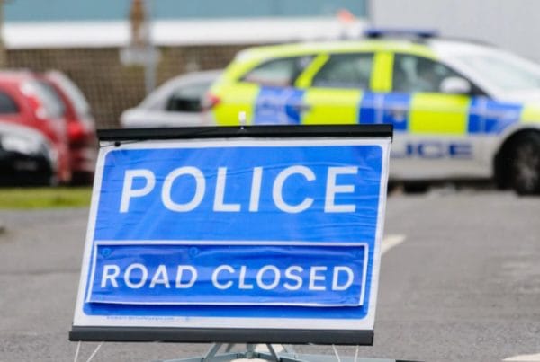 Police road closed sign with police car blocking the road