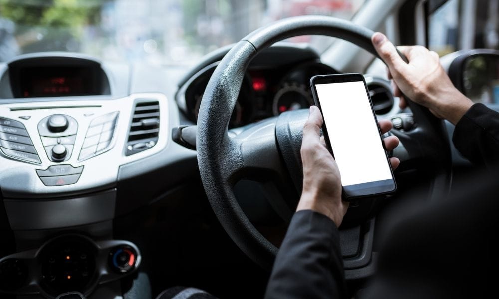 Person using mobile phone behind the wheel