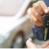 Someone receiving keys, handed over by another person - with a car in the background