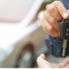 Someone receiving keys, handed over by another person - with a car in the background