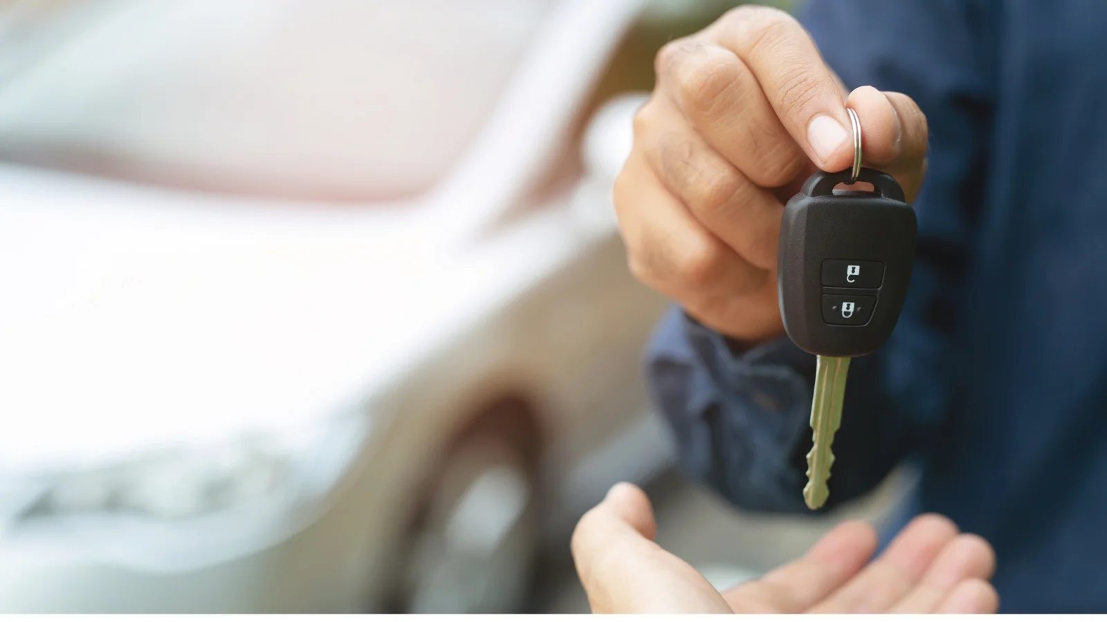 Someone receiving keys, handed over by another person - with a car in the background