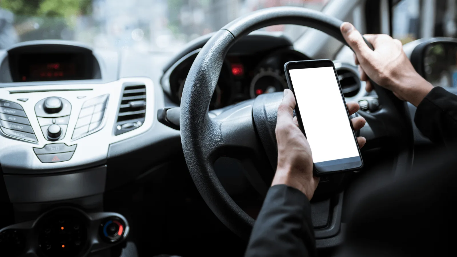 Person using mobile phone behind the wheel