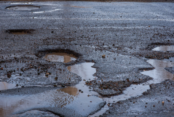 Road with multiple potholes filled with rain water