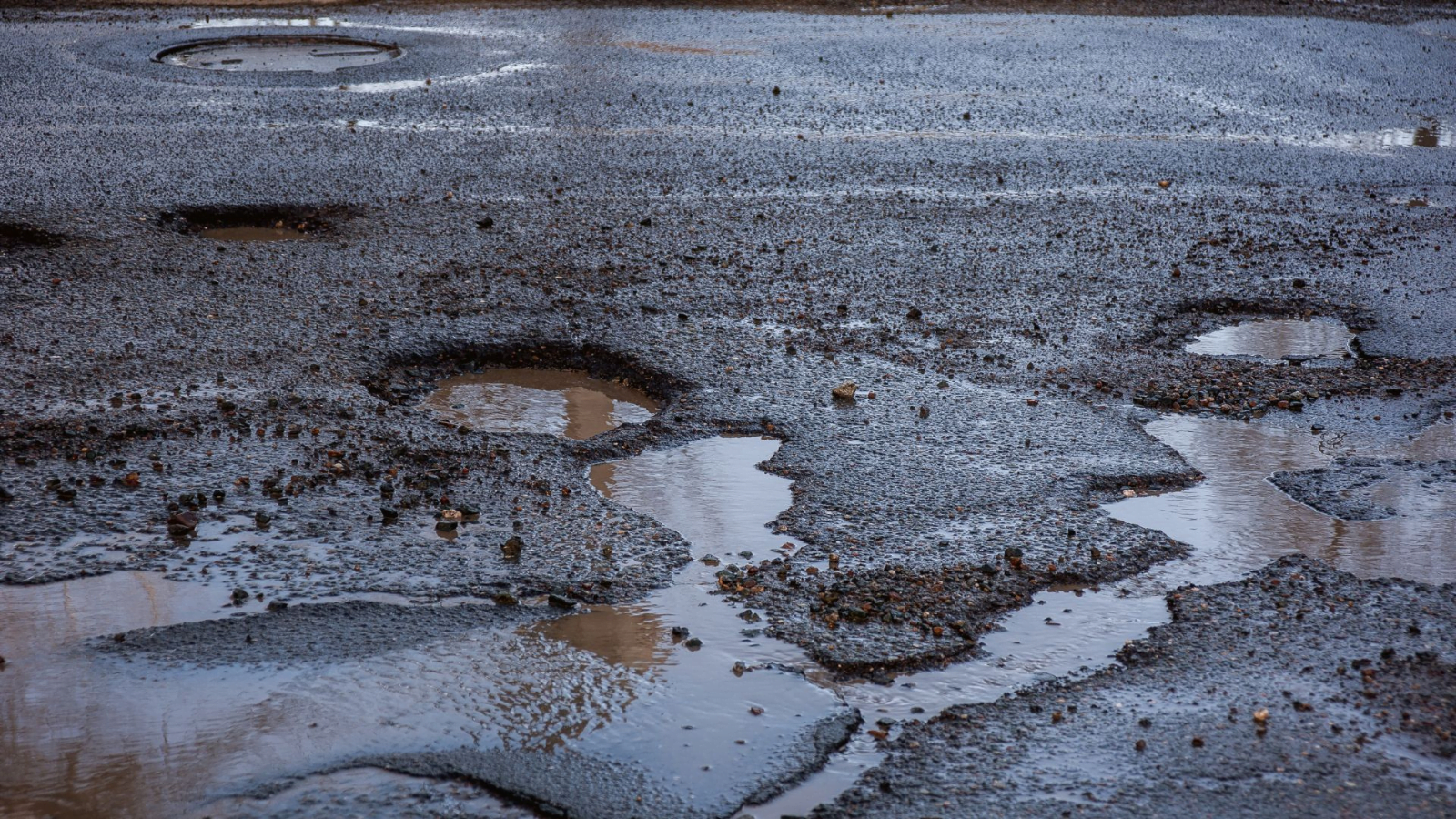 Road with multiple potholes filled with rain water