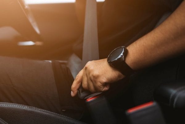 Picture of individual fastening their seatbelt in a car.