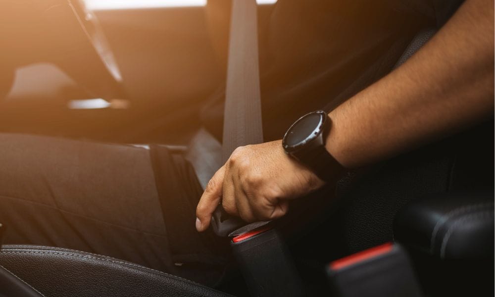 Picture of individual fastening their seatbelt in a car.