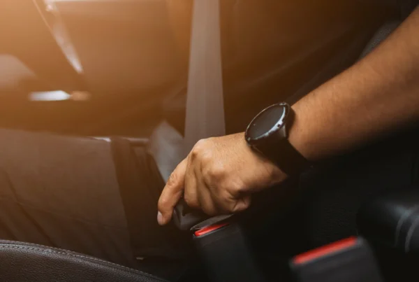 Picture of individual fastening their seatbelt in a car.